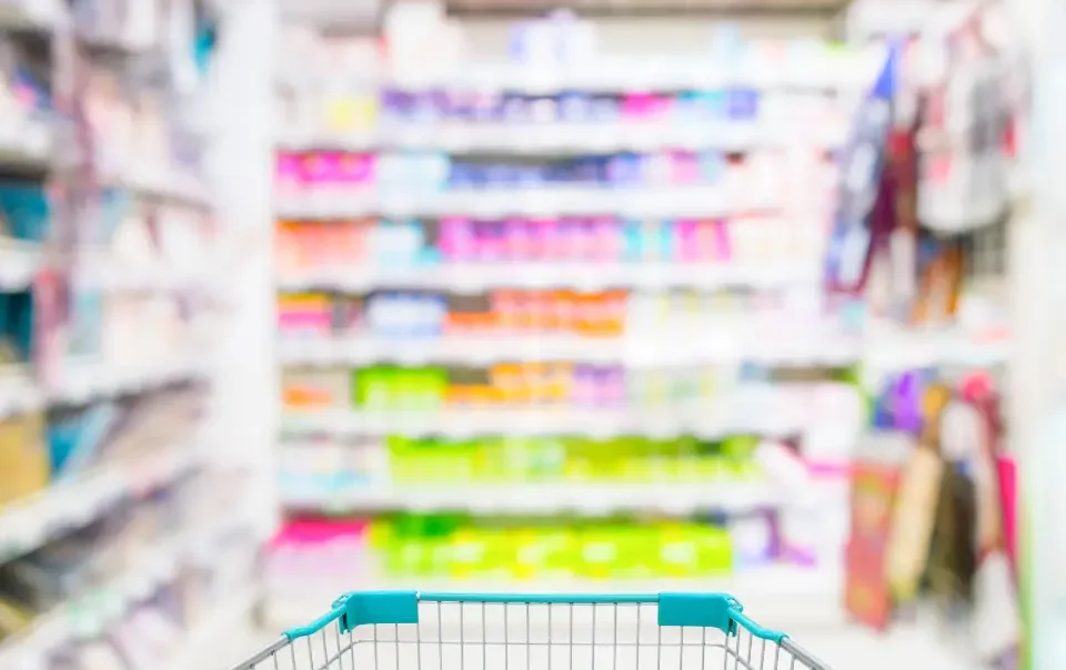 Carrito de compras por un pasillo de supermercado, con góndolas a los costados y al frente