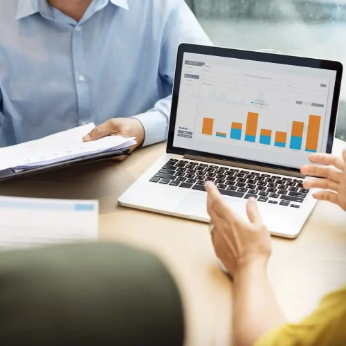 Grupo de trabajo viendo laptop con gráficos de barra